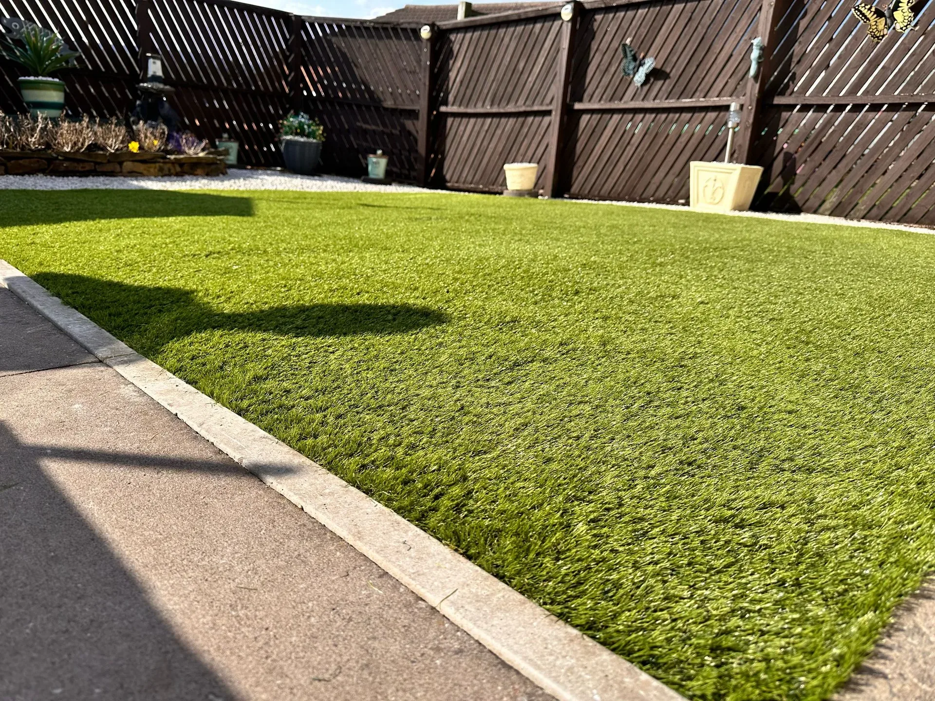 Artificial turf backyard installation bordered by a concrete walkway