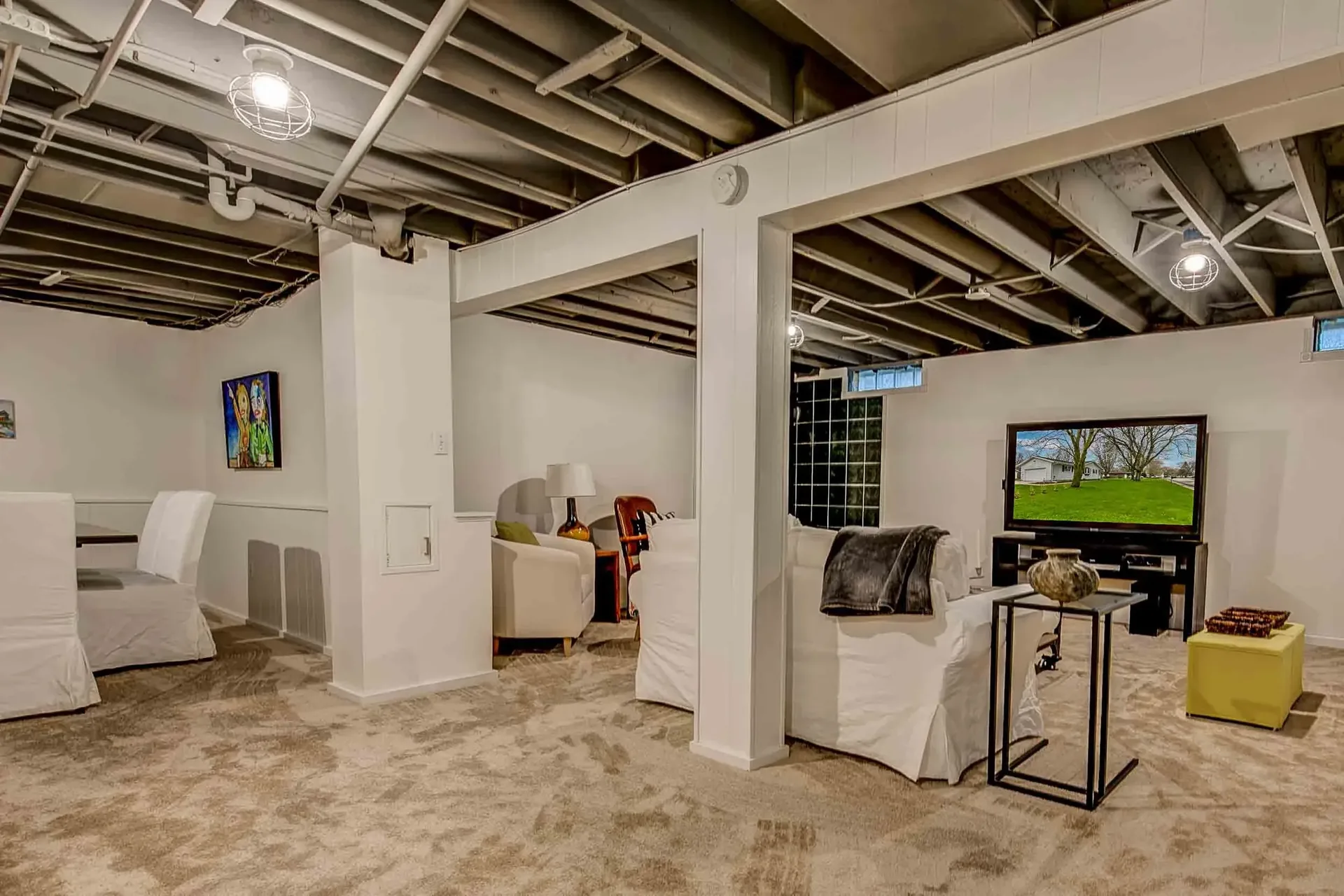 Remodeled basement entertainment area with exposed ceiling and game space