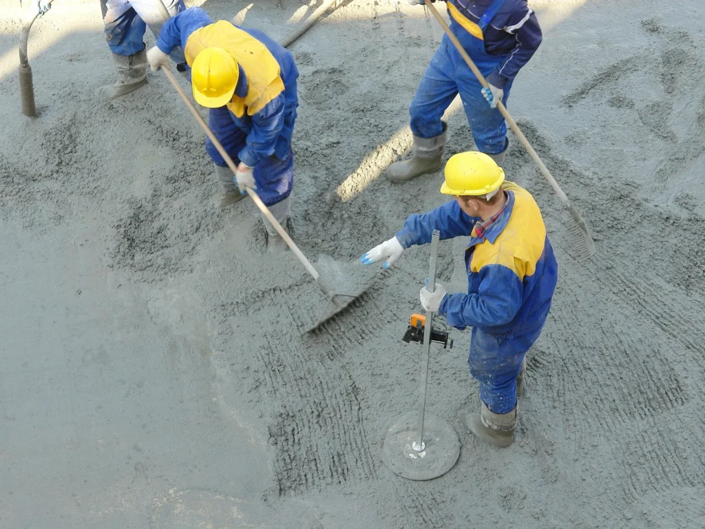 Concrete crew in safety gear screeding and finishing a fresh concrete slab
