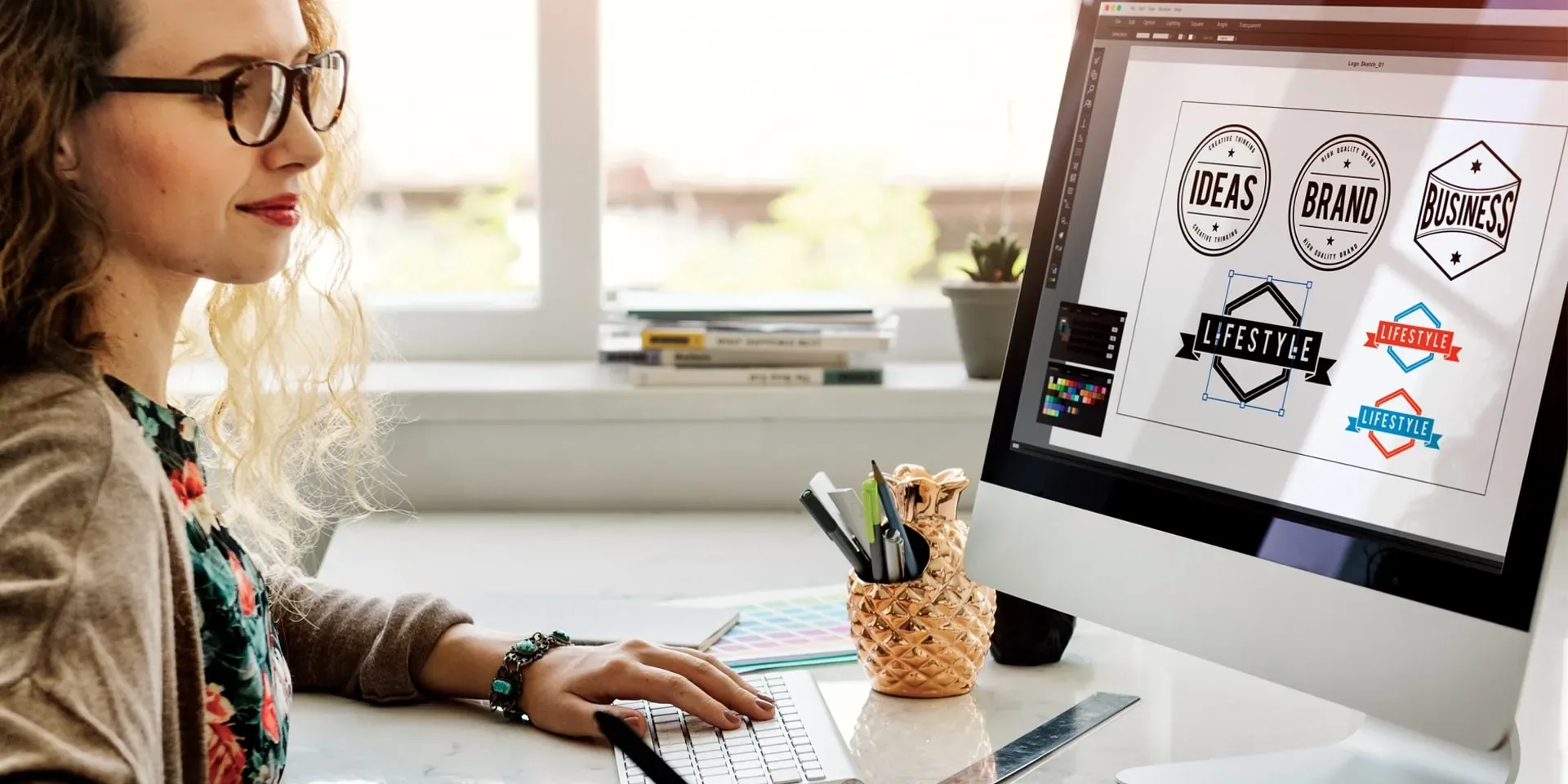 Graphic designer working on brand assets at a desktop computer