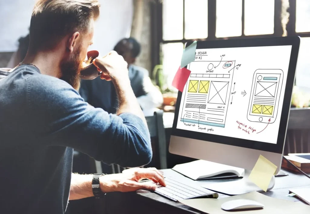 Web designer planning a site layout with wireframes and dual monitors