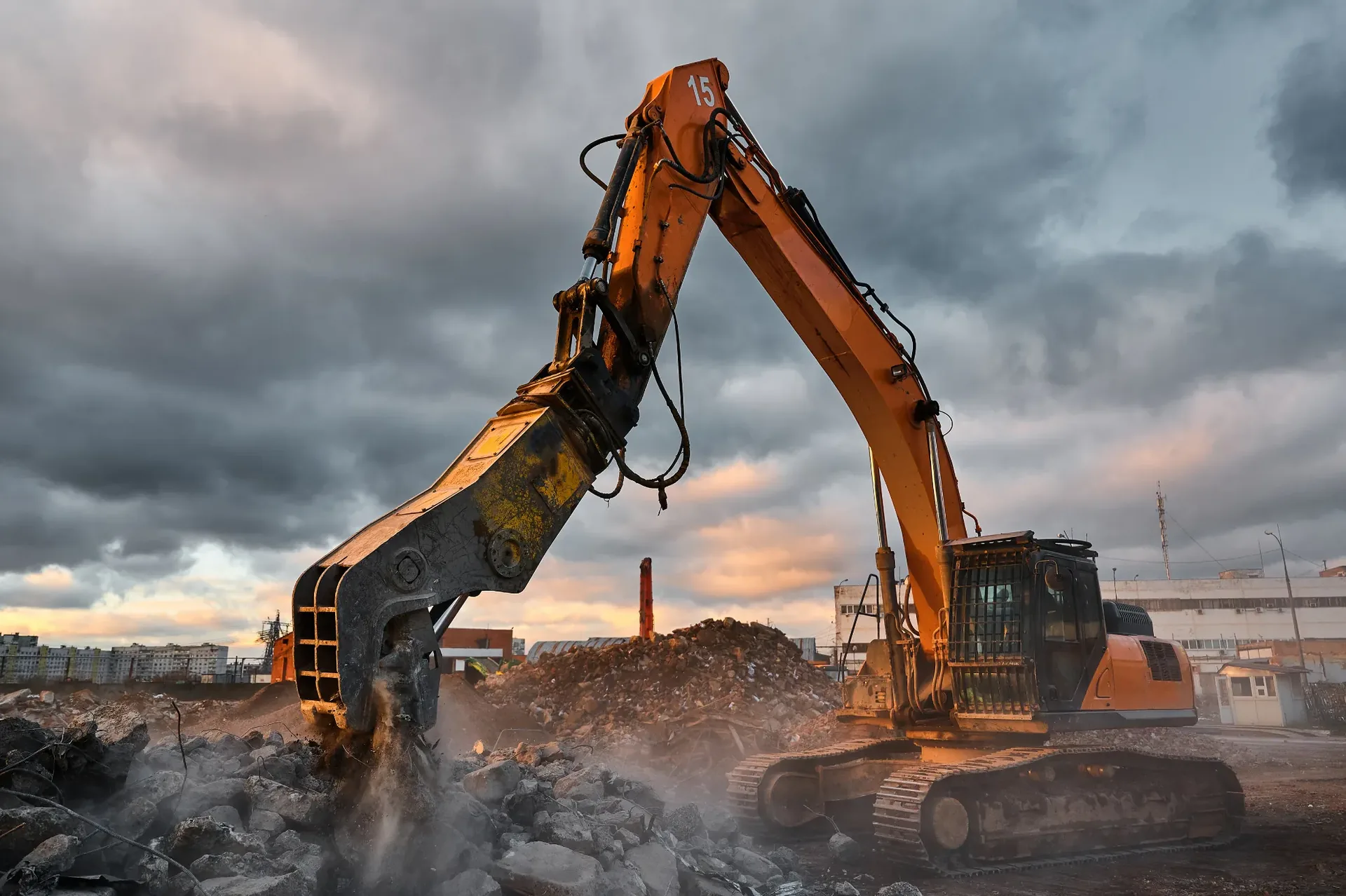 Demolition excavator with a hydraulic breaker working under a dramatic sky