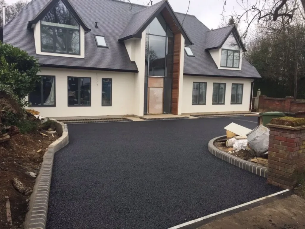 Newly paved asphalt driveway leading to a two story family home