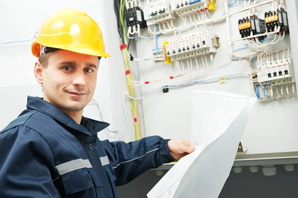 Electrician in a hard hat working at an electrical distribution panel