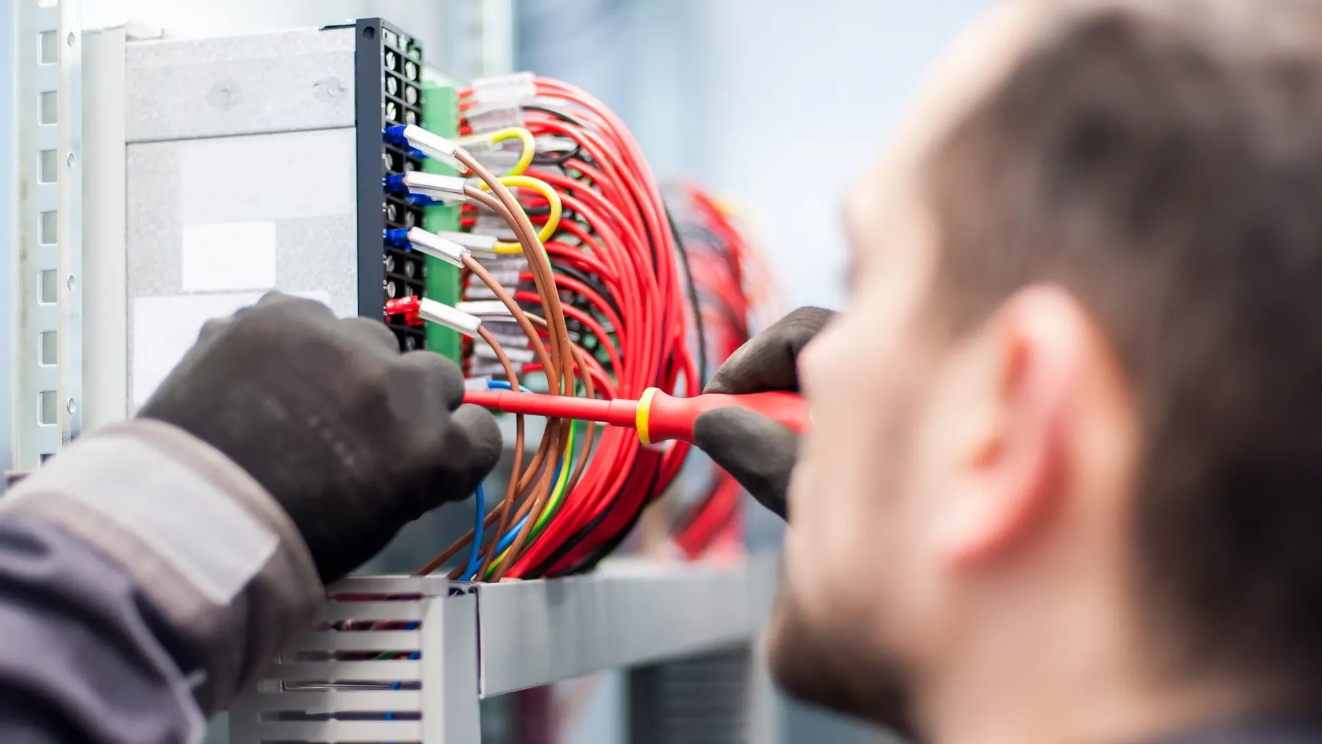 Electrician wiring a service panel with colour coded cables