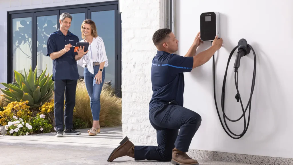 Technician installing a home EV charger while the homeowners watch