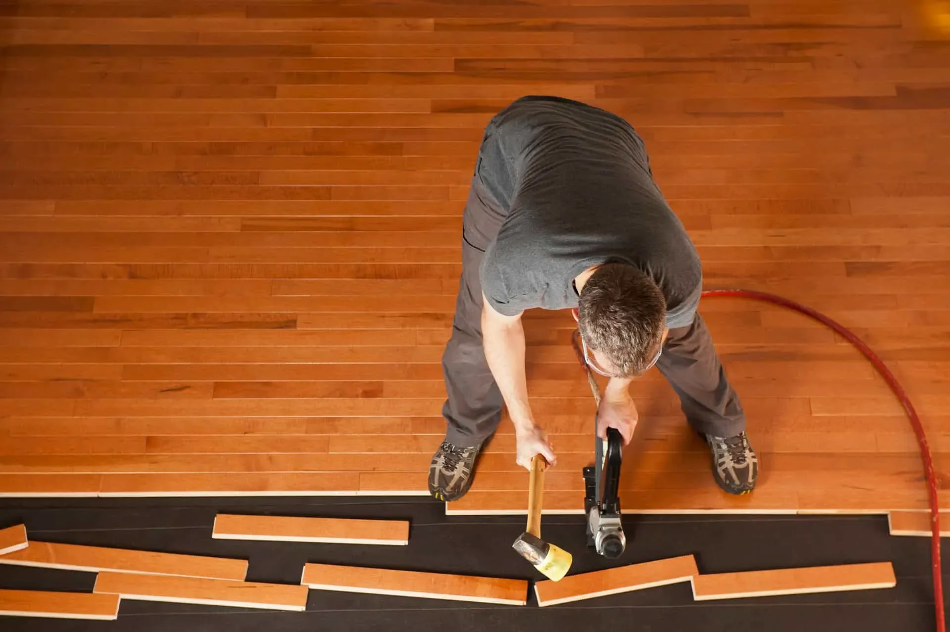 Flooring contractor installing hardwood planks with a nail gun