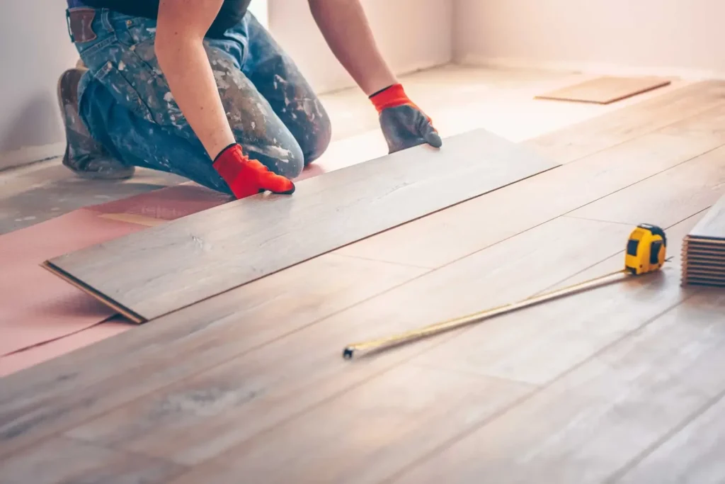 Two flooring installers laying laminate planks in a bright room