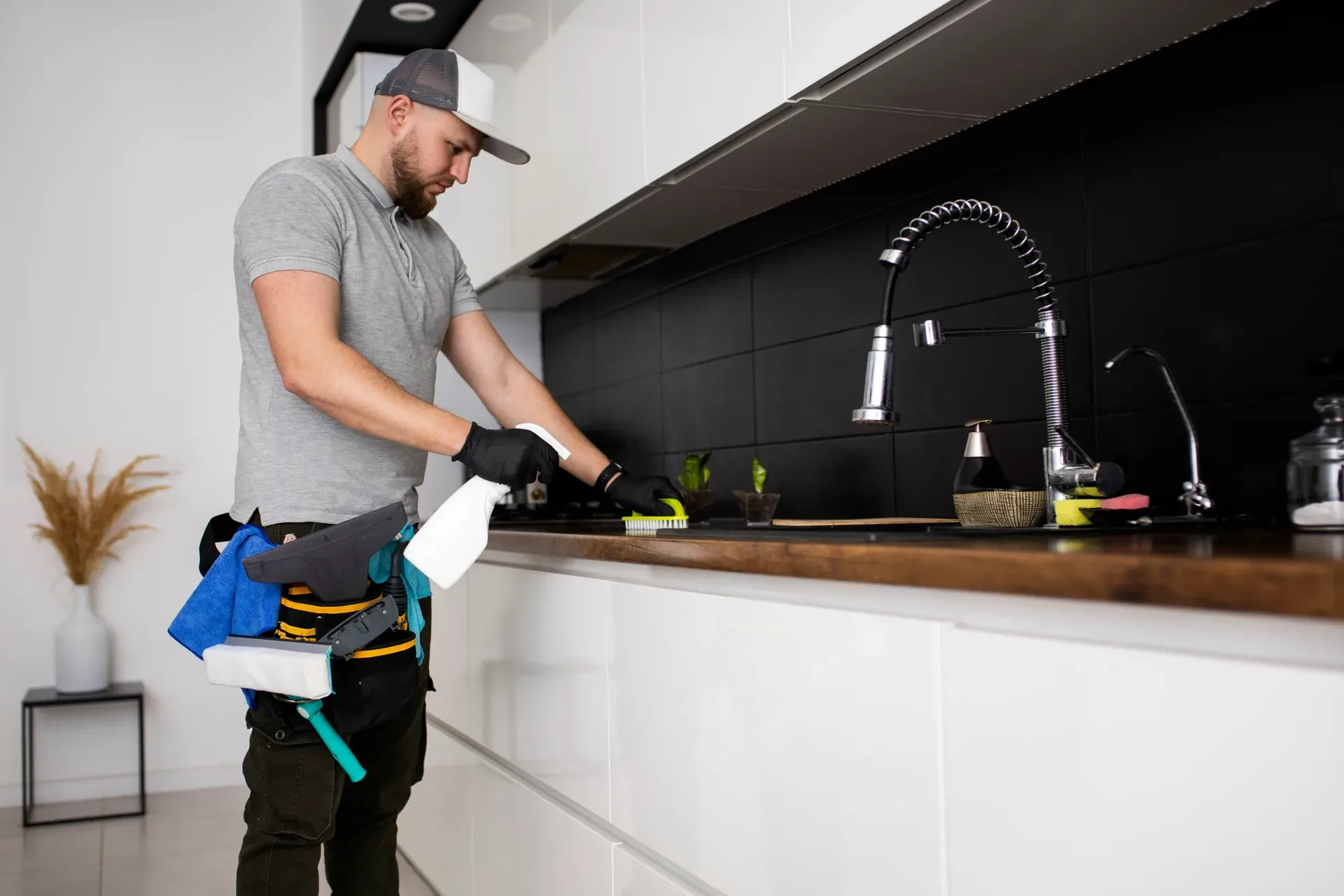 Kitchen remodeling contractor installing fixtures along a dark tile backsplash