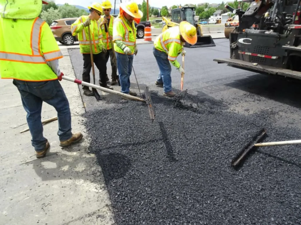 Paving crew in high visibility vests spreading hot asphalt