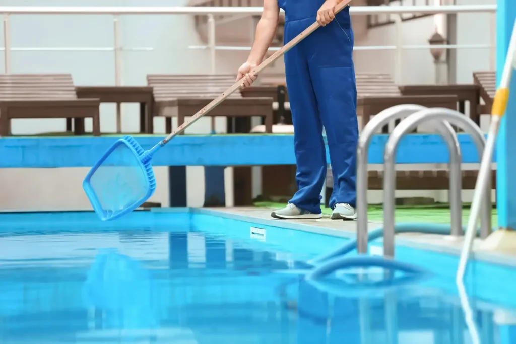 Pool technician skimming and servicing a residential swimming pool