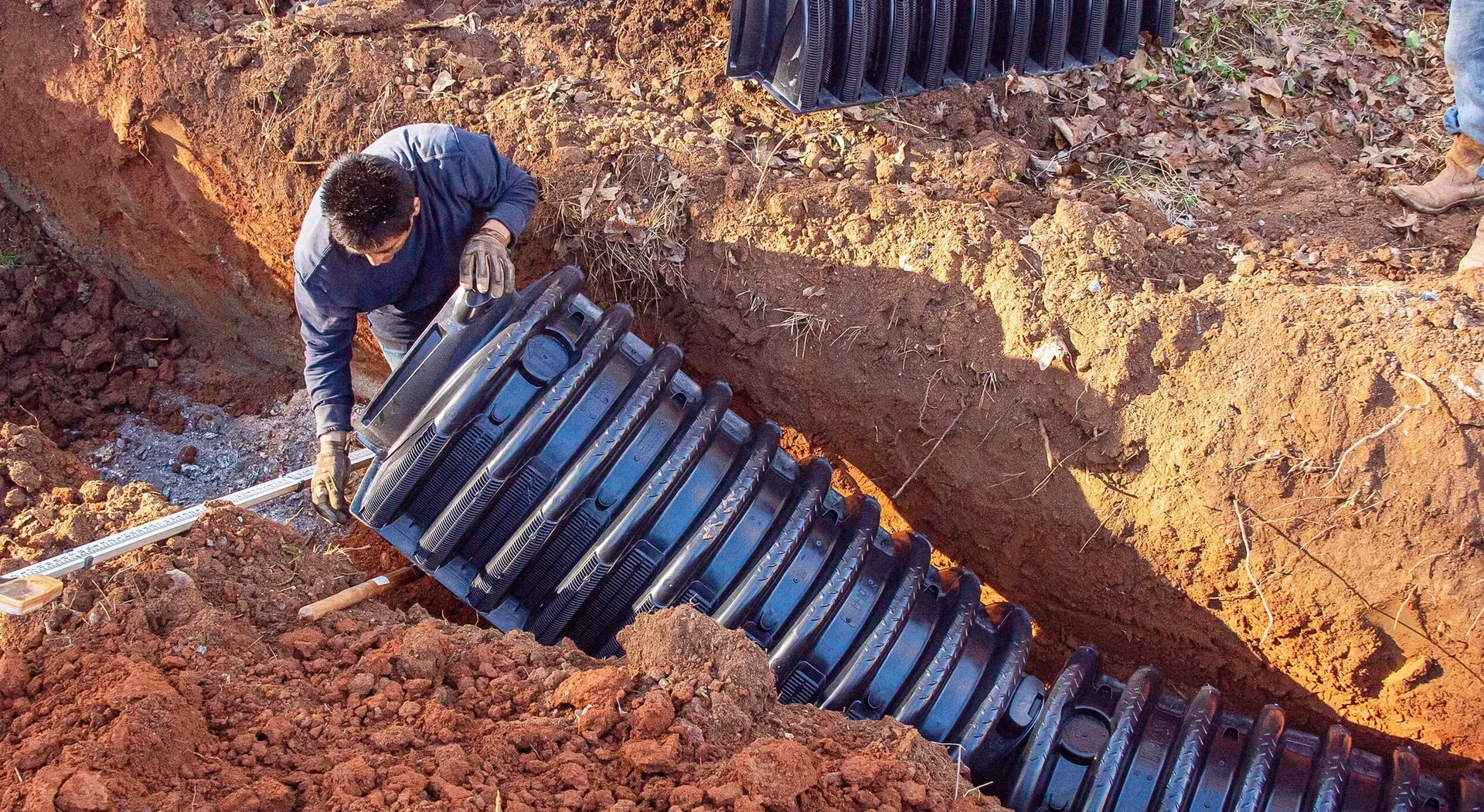 Crew installing a septic tank into an excavated trench