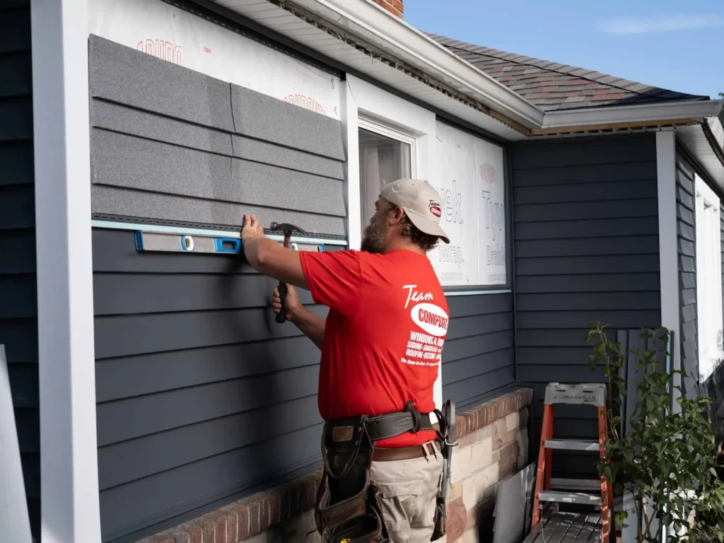 Siding contractor installing vinyl siding panels on a house exterior