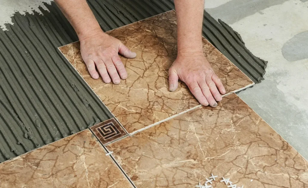 Tile installer setting floor tiles into fresh adhesive