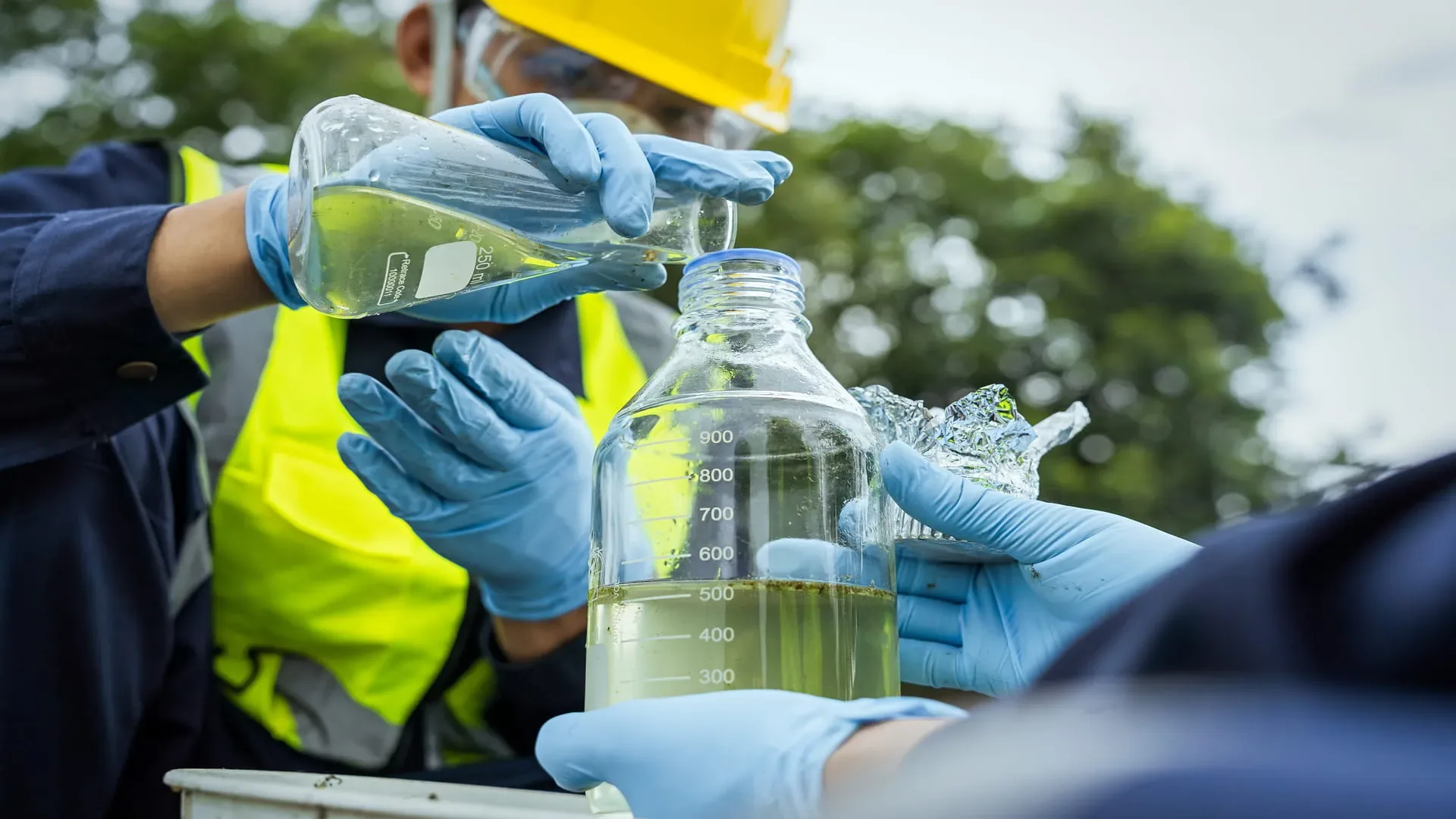 Technician in gloves testing a water quality sample in a glass beaker