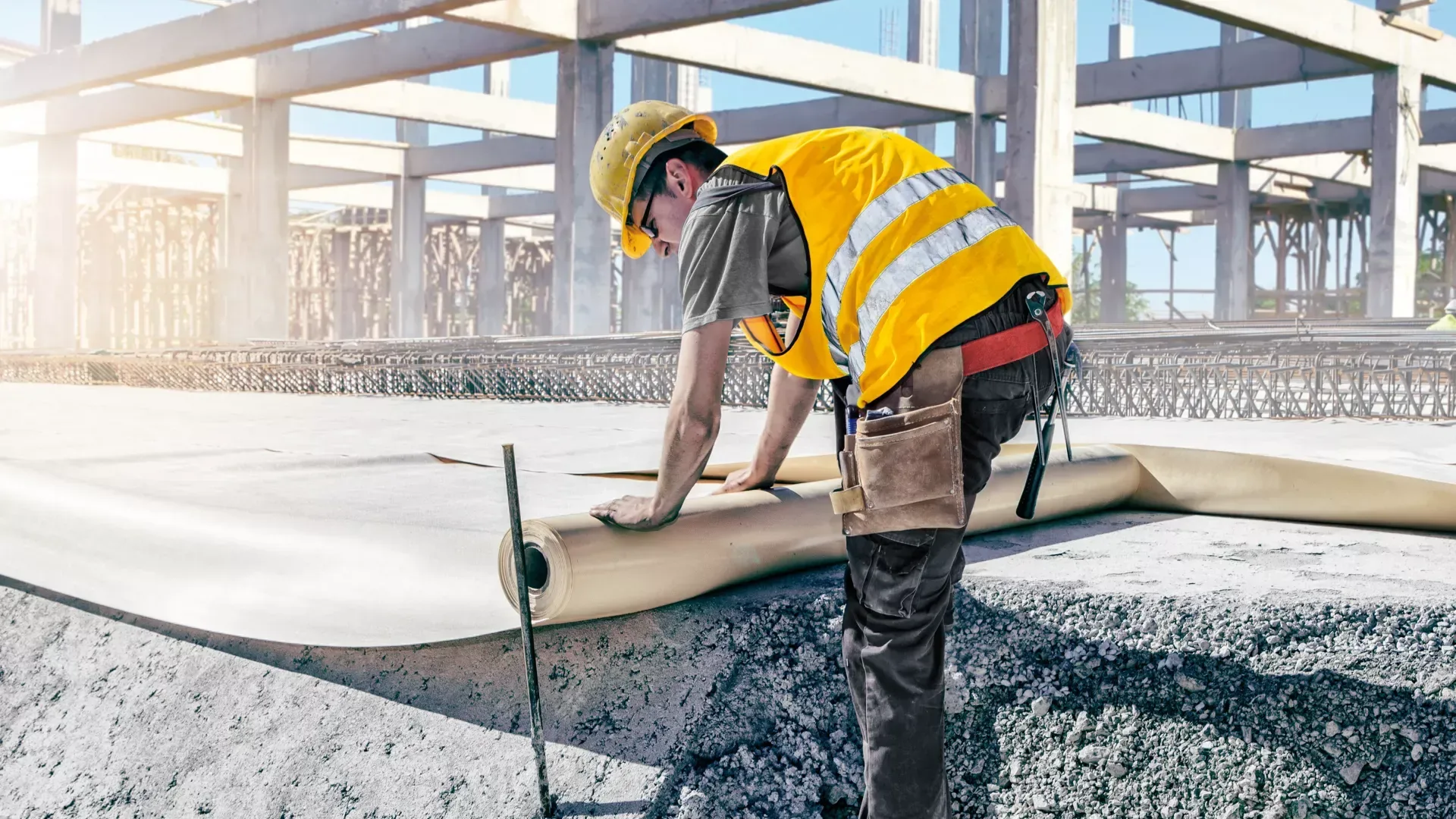 Worker applying a waterproof coating over a prepared concrete deck